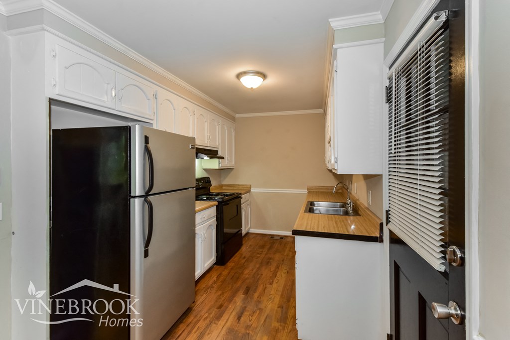 a kitchen with white cabinets and black appliances and a refrigerator