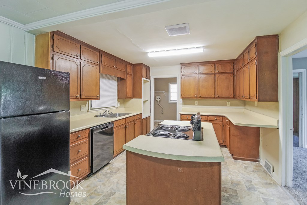 a kitchen with wooden cabinets and white counter tops and a black refrigerator
