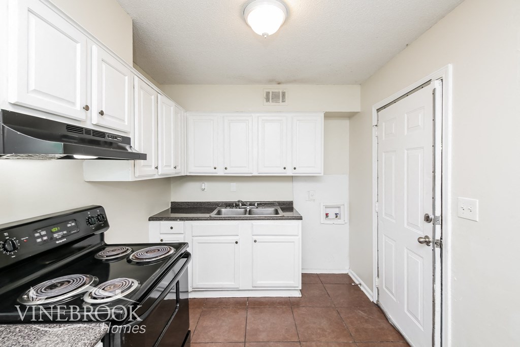 a white kitchen with white cabinets and a stove top oven