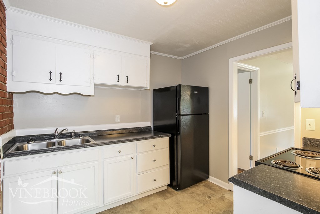 a kitchen with white cabinets and a black refrigerator