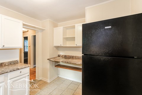 a kitchen with white cabinets and a black refrigerator