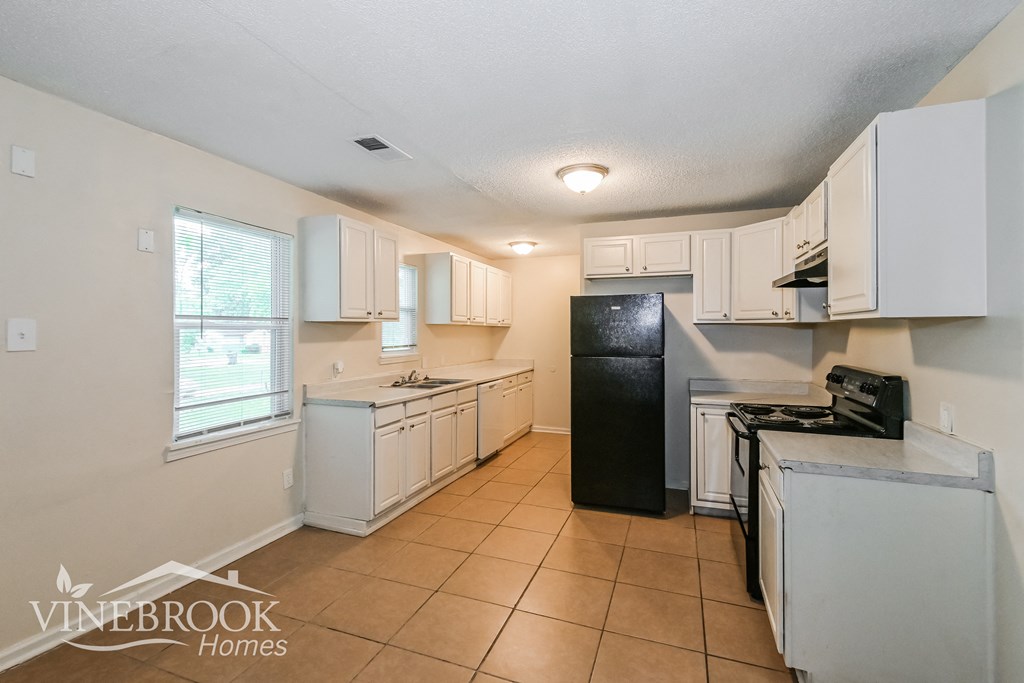 a kitchen with white cabinets and a black refrigerator