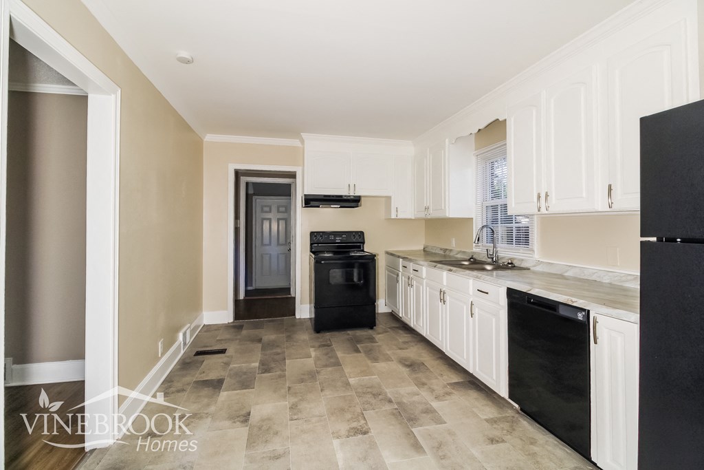 a renovated kitchen with white cabinets and black appliances