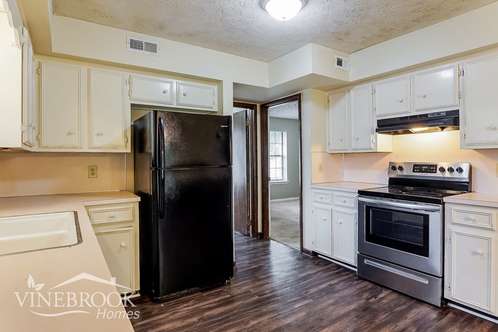 a kitchen with white cabinets and a black refrigerator