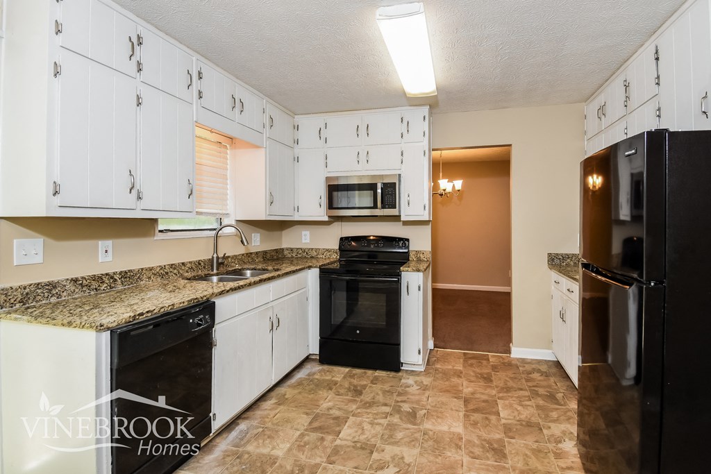 a kitchen with white cabinets and black appliances