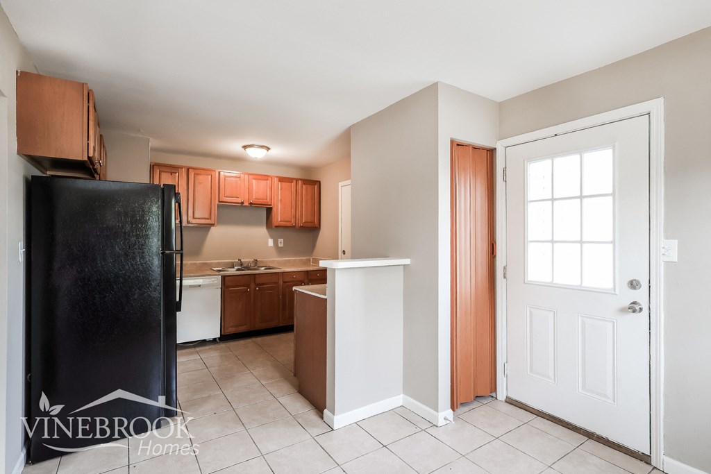 a kitchen with a black refrigerator and wooden cabinets