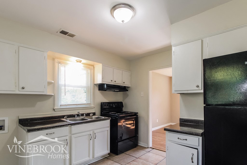a kitchen with white cabinets and black appliances