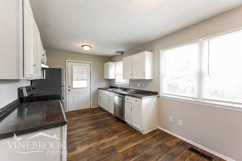 a kitchen with white cabinets and a wood floor