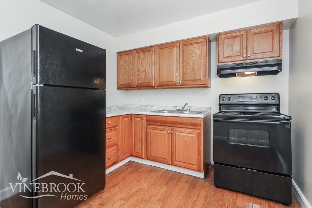 a kitchen with black appliances and wooden cabinets and a black refrigerator