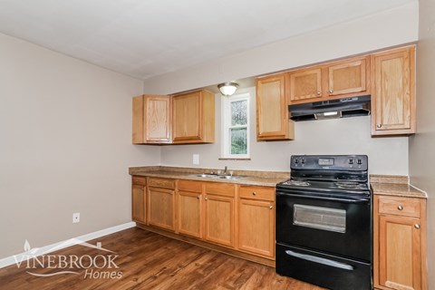 A kitchen with wooden cabinets and a black stove top oven.