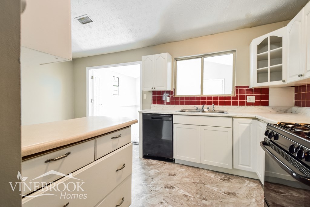 a kitchen with white cabinets and a stove and a sink