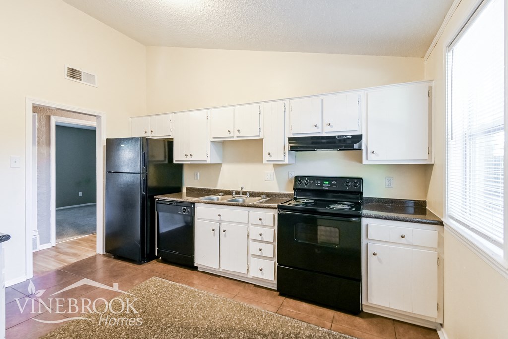 an empty kitchen with black appliances and white cabinets