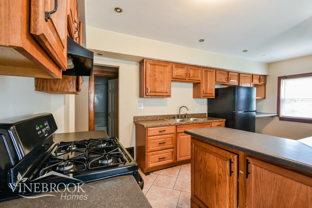 a kitchen with wood cabinets and black appliances and a black stove
