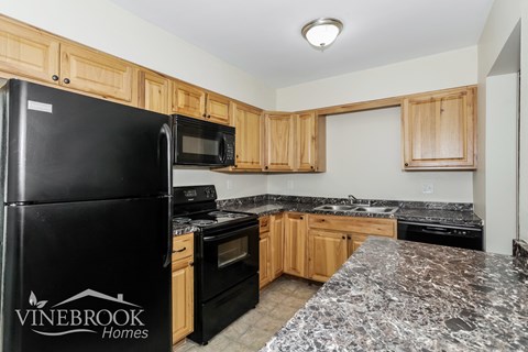 A kitchen with black appliances and wooden cabinets.