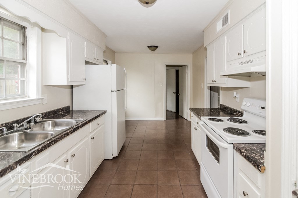 A kitchen with white cabinets and a black stove top.