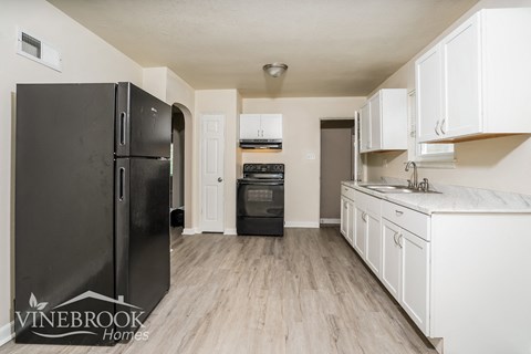 a kitchen with white cabinets and a black refrigerator