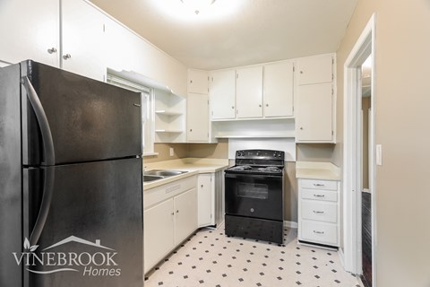 a renovated kitchen with white cabinets and black appliances