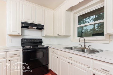 A kitchen with white cabinets and a black stove top oven.