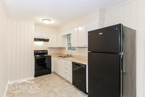 a white kitchen with black appliances and white cabinets