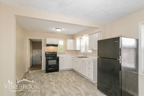 a kitchen with white cabinets and black appliances and a refrigerator