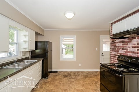 A kitchen with a black refrigerator and a black stove top oven.