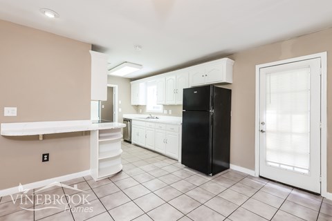 A kitchen with black appliances and white cabinets.