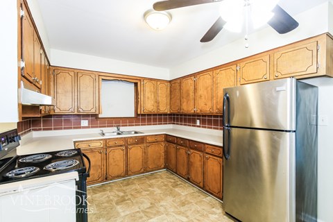 A kitchen with wooden cabinets and a stainless steel refrigerator.