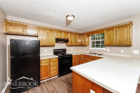A kitchen with wooden cabinets and black appliances.