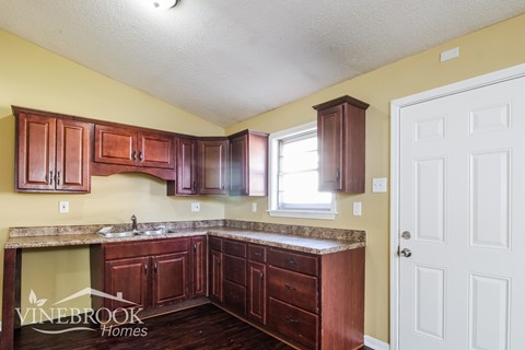 A kitchen with wooden cabinets and a white door.