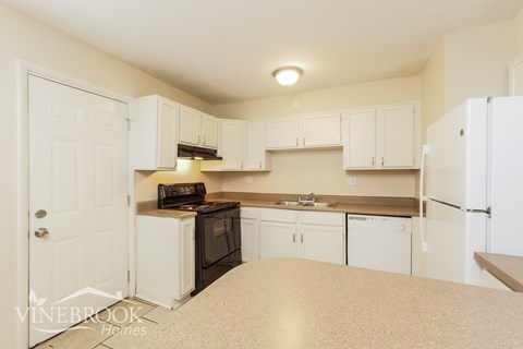 A kitchen with white cabinets and appliances.