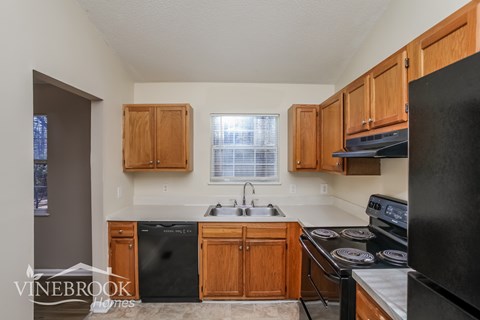 A kitchen with wooden cabinets and black appliances.