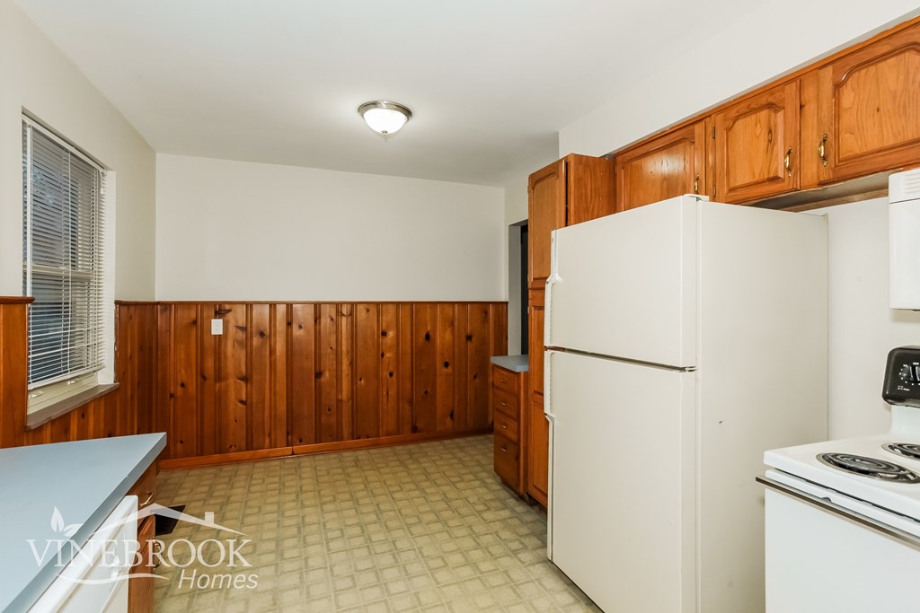 A kitchen with wooden cabinets and a white refrigerator.