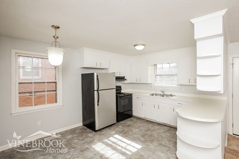 A kitchen with a black refrigerator and white cabinets.
