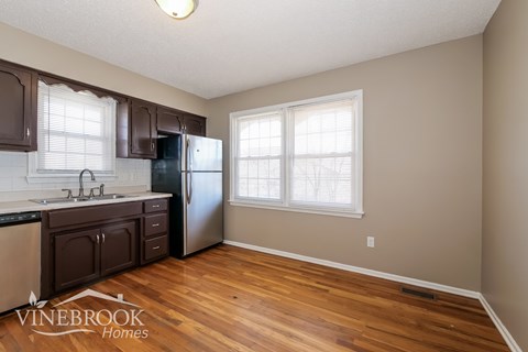 A kitchen with wood floors and a Vinebrook Homes logo.