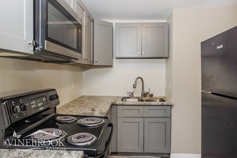 A kitchen with a black stove top oven and a black refrigerator.