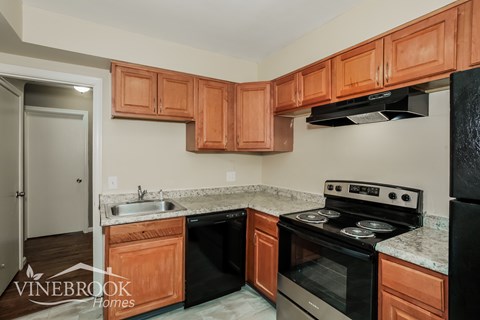A kitchen with black appliances and wooden cabinets.