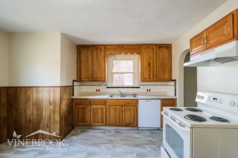 A kitchen with wooden cabinets and a white stove top oven.