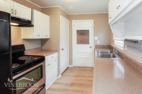 A kitchen with a black stove top oven and white cabinets.