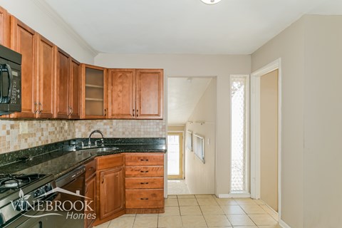 A kitchen with wooden cabinets and a black counter top.