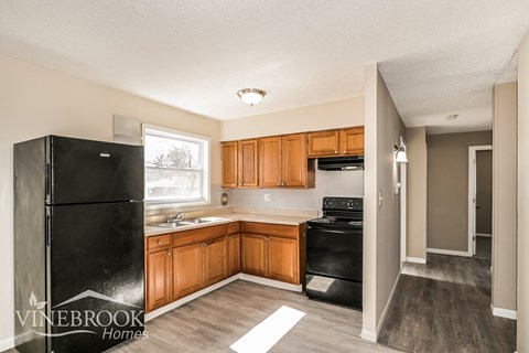 A kitchen with wooden cabinets and a black fridge.
