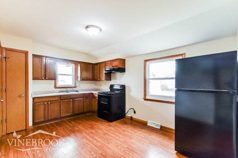 A kitchen with wood floors and a refrigerator.