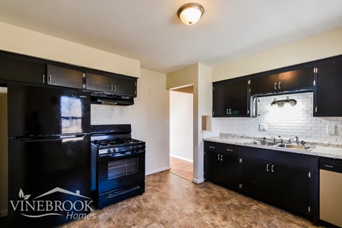 A kitchen with black appliances and cabinets is on the market.