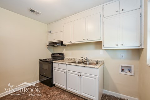 A kitchen with white cabinets and a granite countertop.