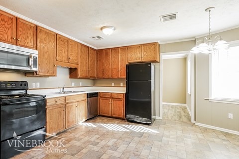 A kitchen with wooden cabinets and a black refrigerator.