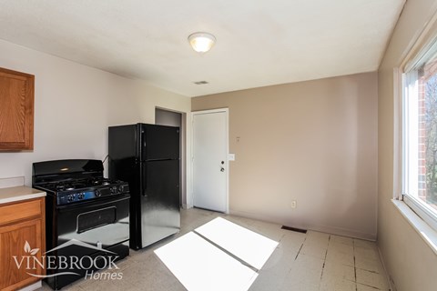 A kitchen with a black stove and refrigerator in a room with a white door.