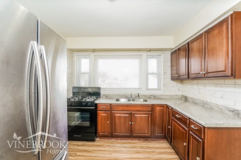 A kitchen with wooden cabinets and a marble countertop.