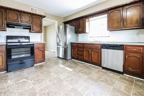 A kitchen with brown cabinets and a tiled floor.
