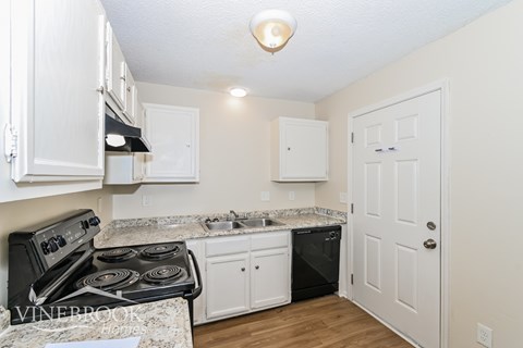 A kitchen with a black stove top oven and white cabinets.