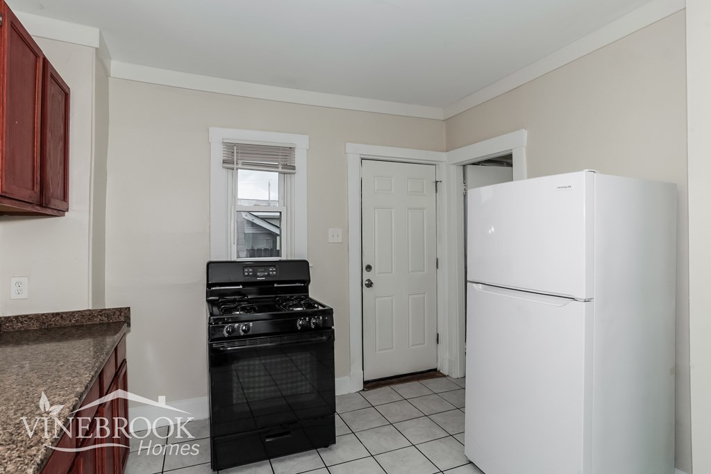 A kitchen with a black stove top oven and a white refrigerator.