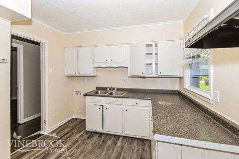 A kitchen with white cabinets and a sink is shown.